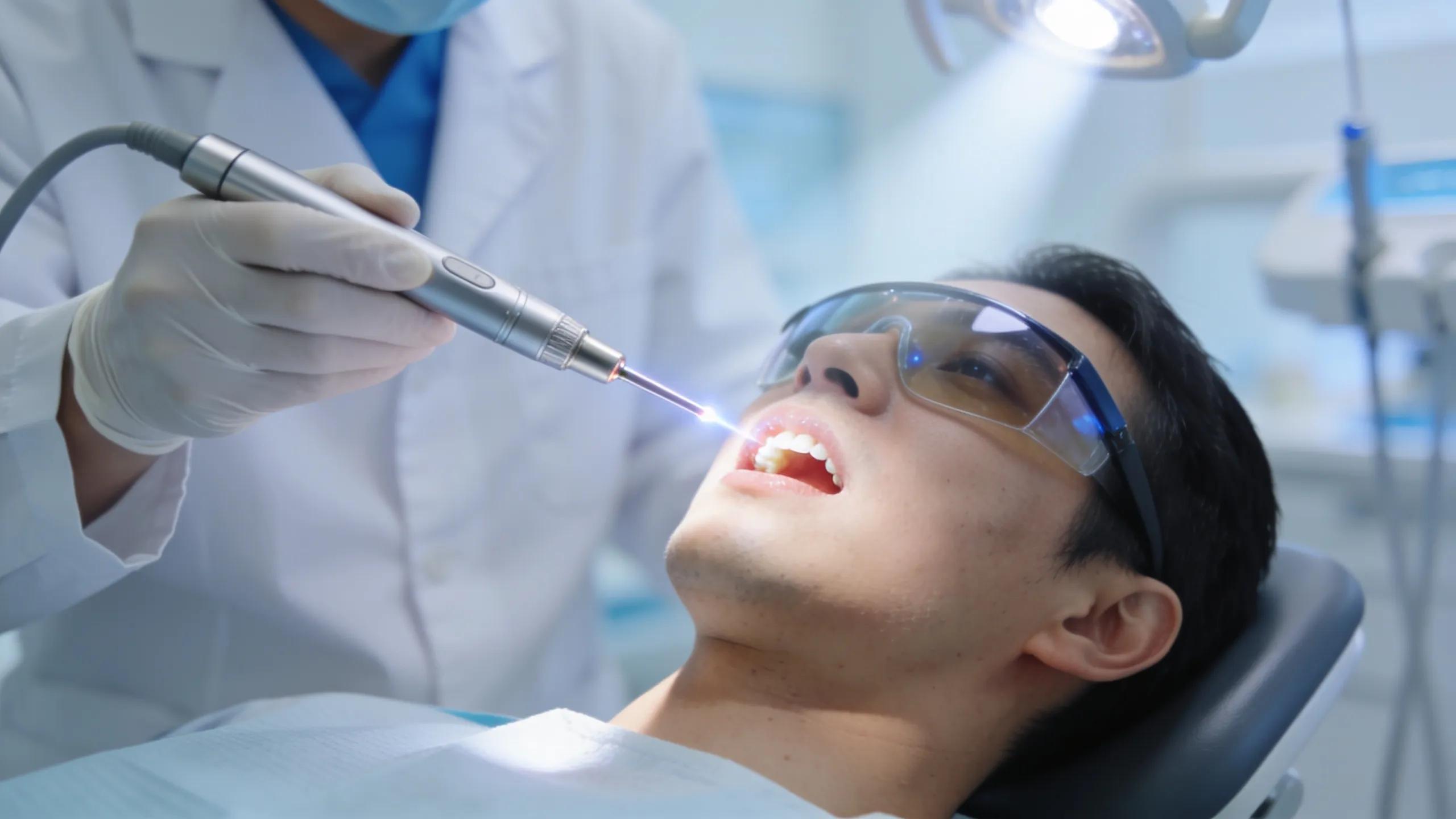 Dentist using laser technology on a patient during a dental procedure illustrating treatment precision